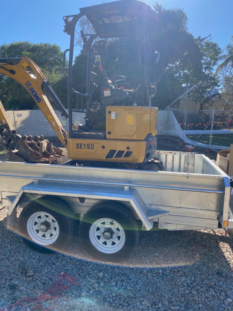 XCMG 19UE mini excavator secured on a trailer for transport.